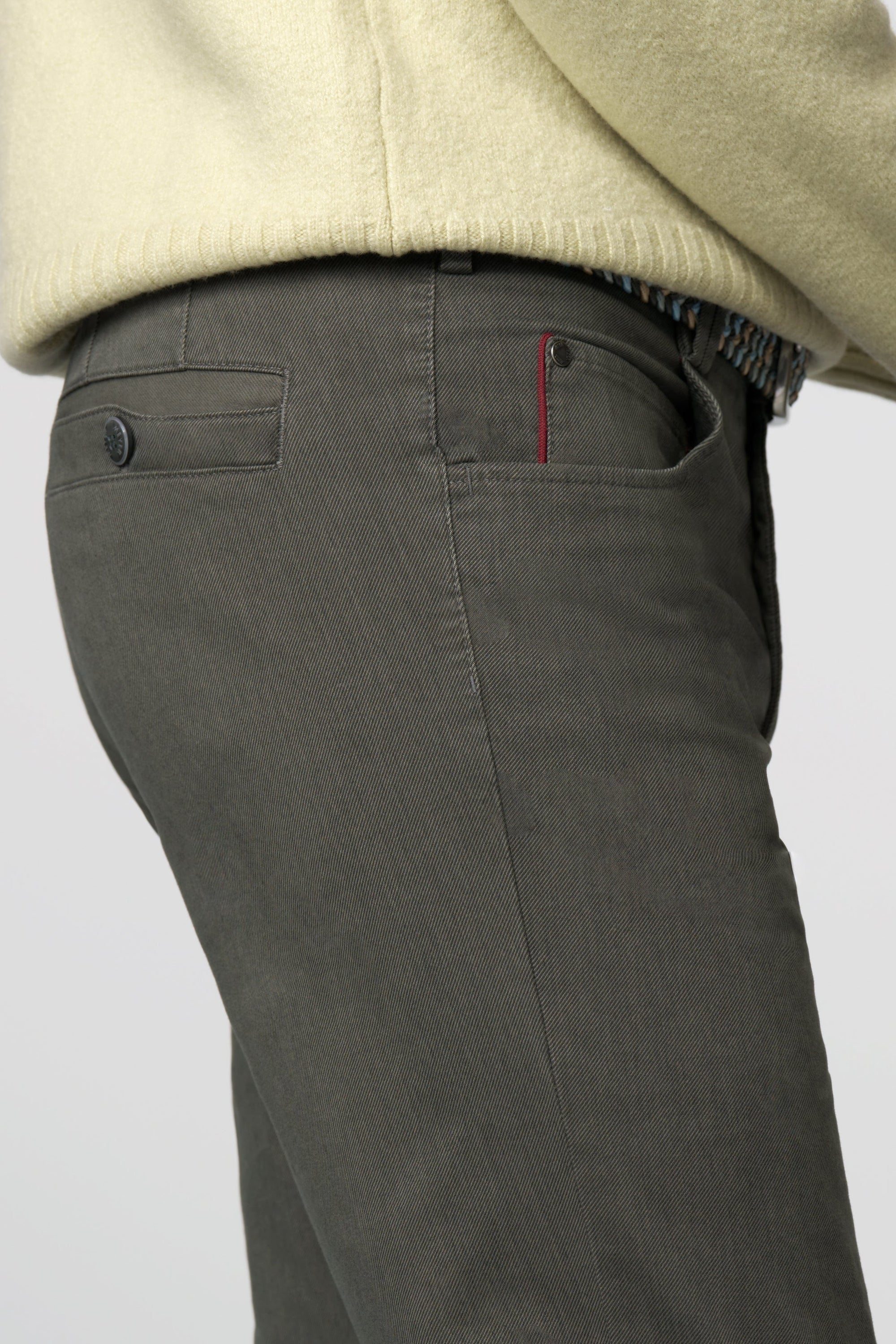 Dark gray pants with a beige sweater on a light gray background